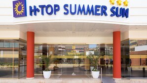 Entrada de un hotel con un cartel que dice "HOTOP SUMMER SUN" y un logo de sol.