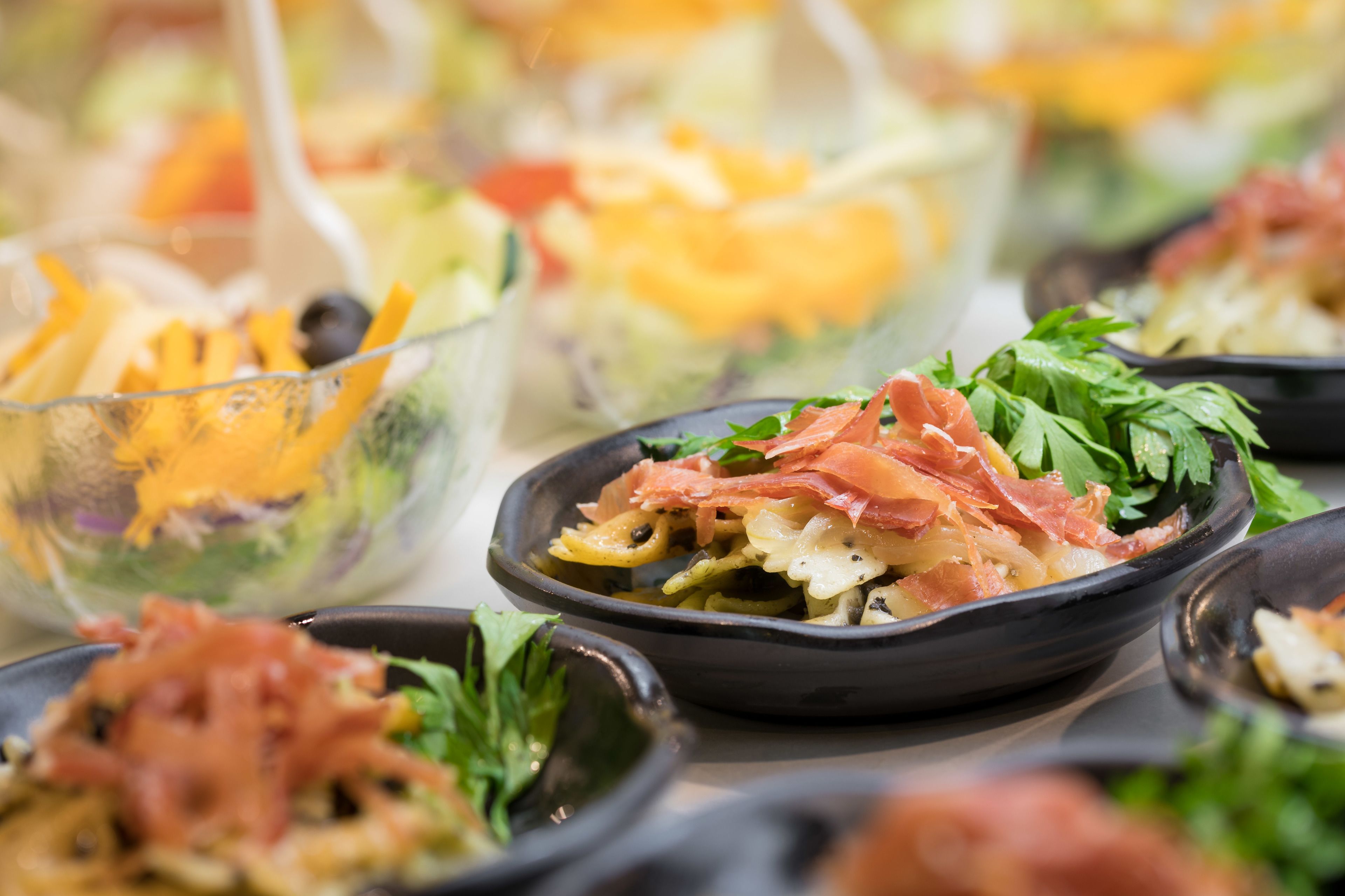 Una variedad de platos de comida, incluyendo ensaladas y pasta, dispuestos sobre una mesa.