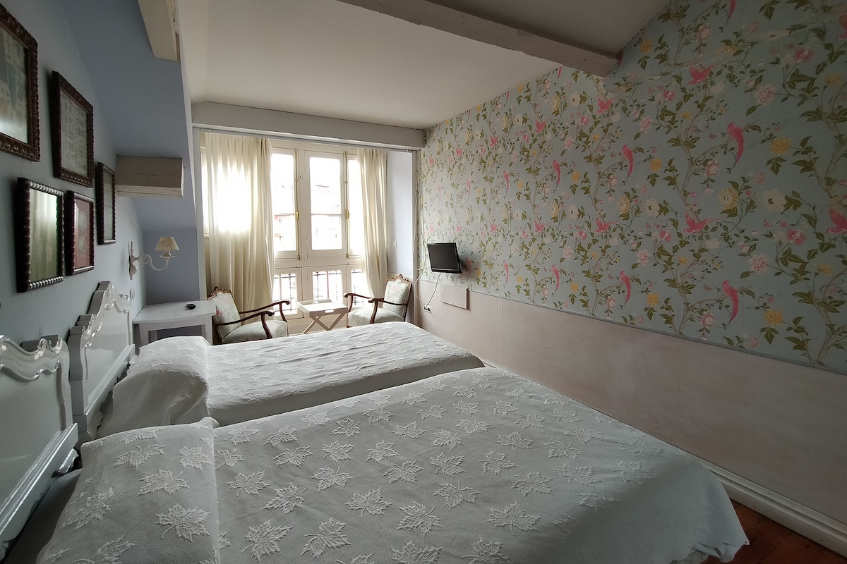A room with two beds, a desk, a chair, and a TV.