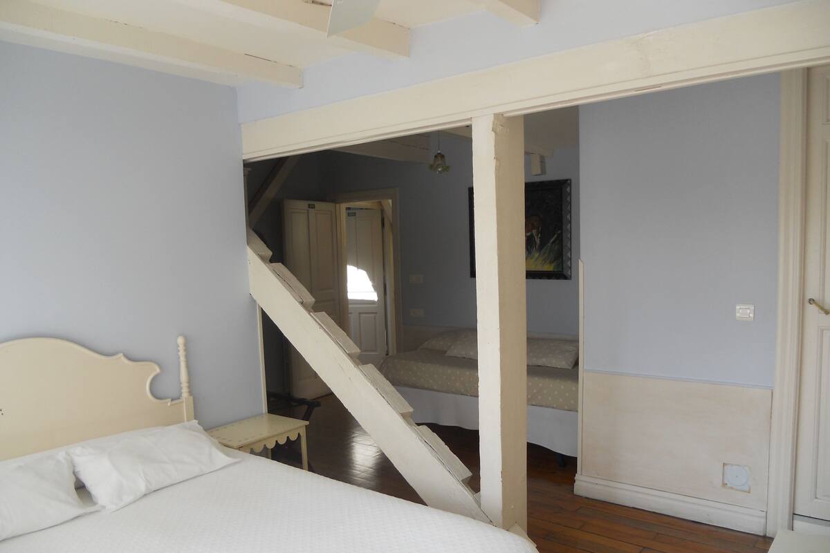 A bedroom with a bed, a staircase leading to another room, and a door.