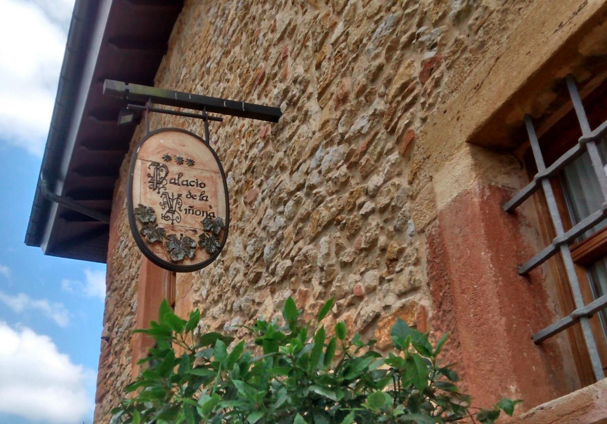 Un edificio rústico con fachada de piedra y un letrero colgante que dice "Palacio de la Luna".