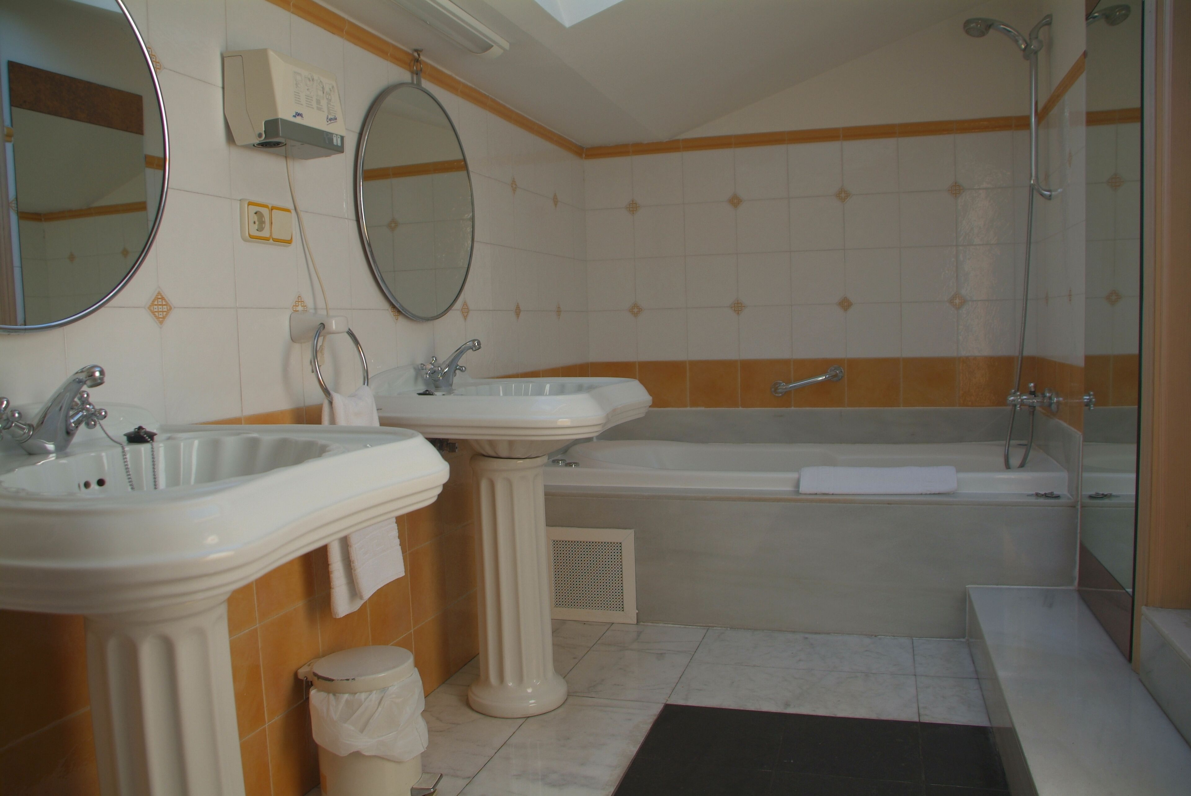 Een badkamer met twee wastafels, een bad en een douche.
