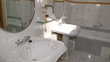 A bathroom with a white sink, a glass shelf, a mirror, and a bathtub.