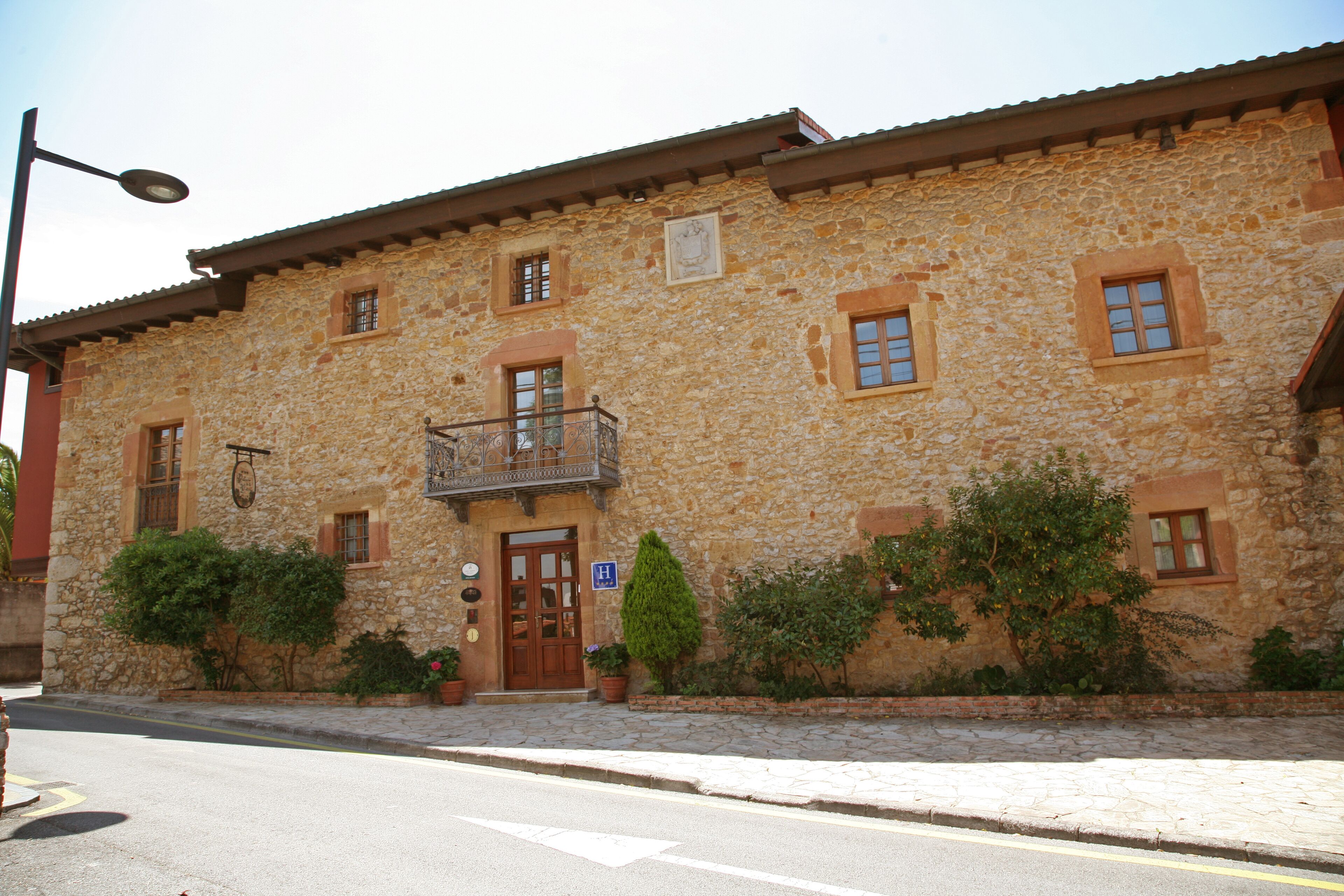 A stone building with a central entrance, a small balcony, and a street lamp.