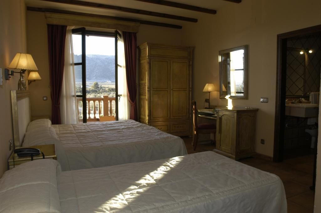 Habitación de hotel con dos camas, un escritorio, una silla, un armario y un baño.