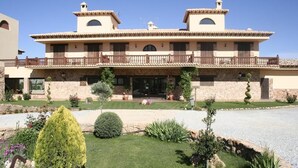 A two-story building with a balcony, stone facade, and a well-maintained garden. - Rural Los Nogales (Pozo Alcon)