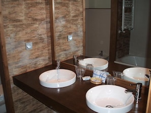 Un baño con dos lavamanos, un espejo y un perchero para toallas.