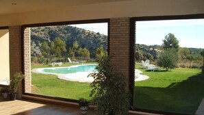 A spacious room with large windows overlooking a swimming pool and a grassy yard. - Rural Los Nogales (Pozo Alcon)