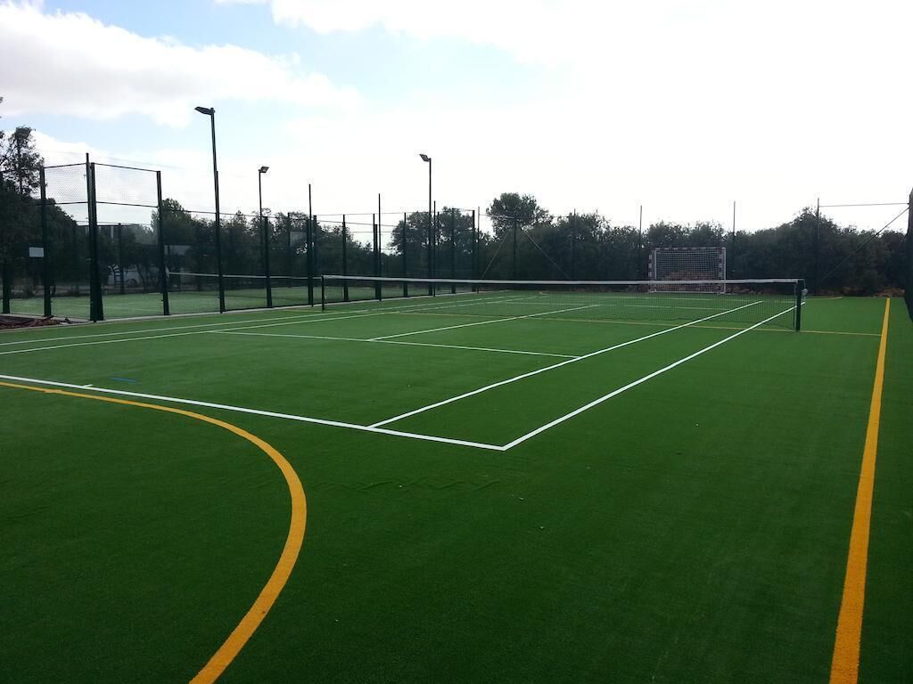 Una pista de tennis amb xarxa, línies delimitadores i pals de llum.