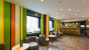 Zona de bar moderna con franjas verticales de colores en las paredes, asientos redondos y una barra con taburetes.