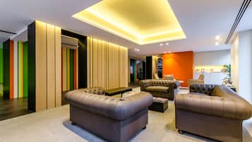 Un salon moderne avec deux canapés en cuir marron, une table basse et un luminaire au plafond qui diffuse une lumière vive.