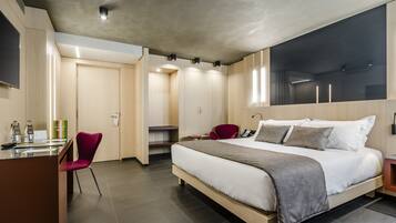 Una habitación de hotel moderna con una cama grande, un escritorio con silla y un armario.