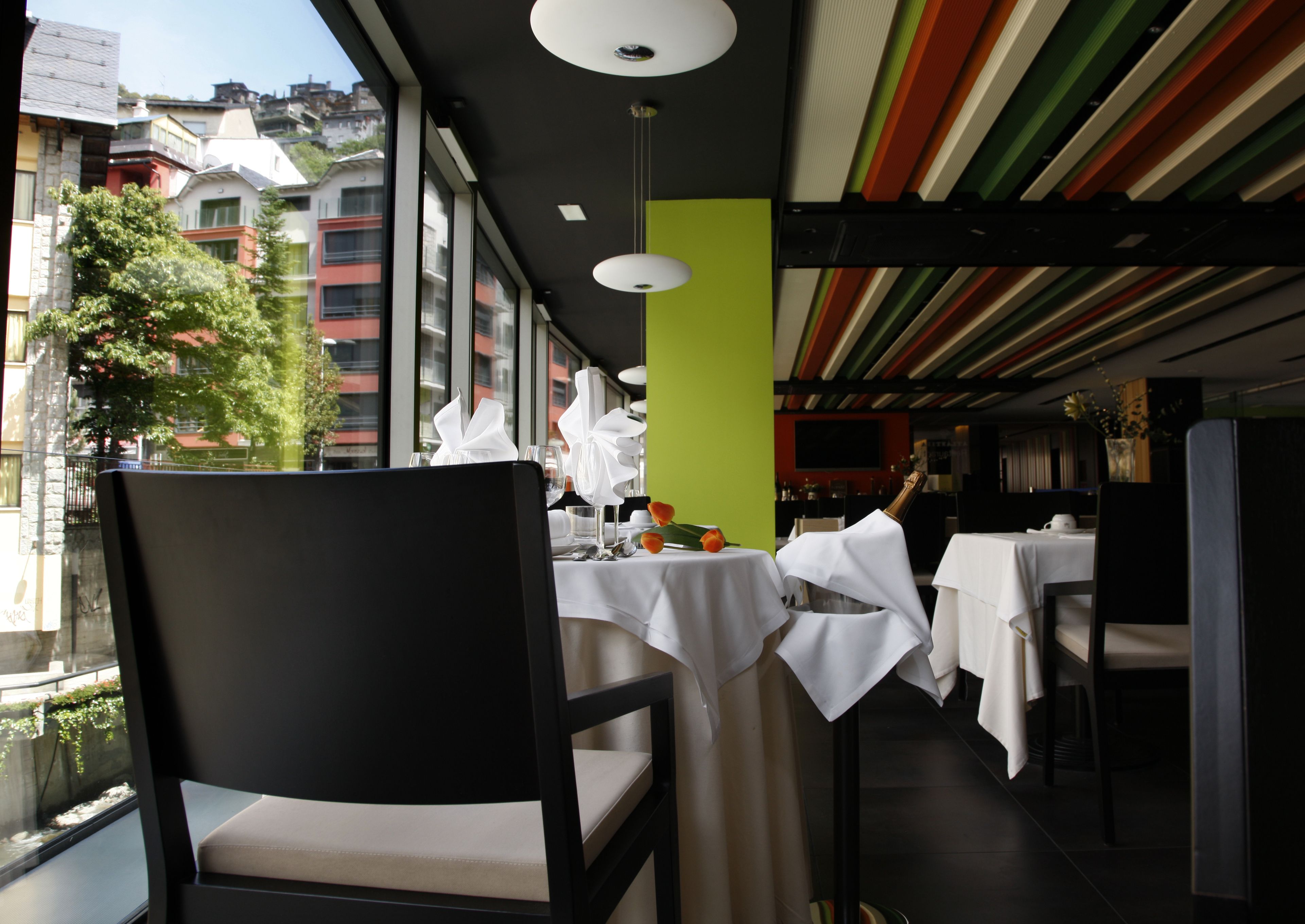 Ein Restaurant mit gedeckten Tischen, Blick auf die Stadt durch große Fenster und einem modernen Innenraum.