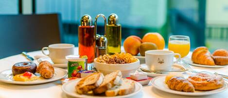 A breakfast table with various foods, drinks, and condiments.