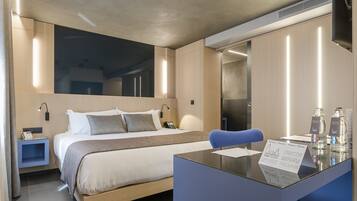 Una habitación de hotel moderna con cama, mesita de noche, escritorio y espejo.