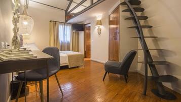 Habitación de hotel con cama, escritorio, silla y una escalera de caracol.
