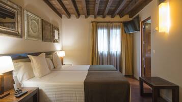 Habitación de hotel con dos camas, techo de madera, televisor y ventana con cortinas.