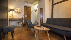 Una sala de estar moderna con un sofá, dos sillones, una mesita de madera y una lámpara.