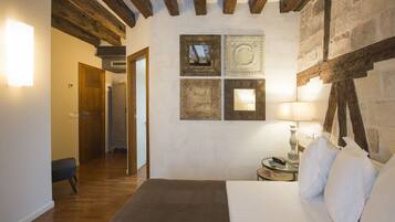 Un dormitorio con techo de madera, una cama, una mesita de noche con lámpara y una pared decorada con platos.