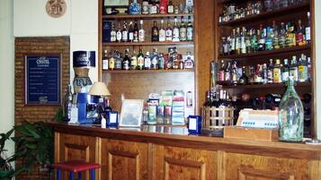 A bar area with wooden shelves stocked with various liquor bottles, a framed menu, and a bar counter with stools.