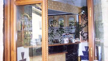 Zona de recepción de un hotel con estructura de madera, pared de azulejos y mostrador con folletos.