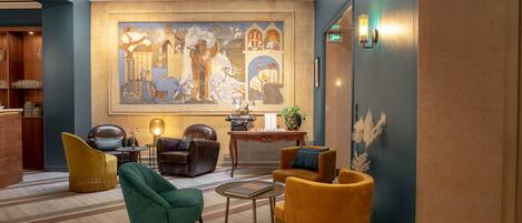 A spacious lobby with a large mural, comfortable seating, a reception desk, and a modern light fixture.