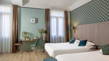Una habitación de hotel con dos camas, un escritorio, una silla y una mesita.