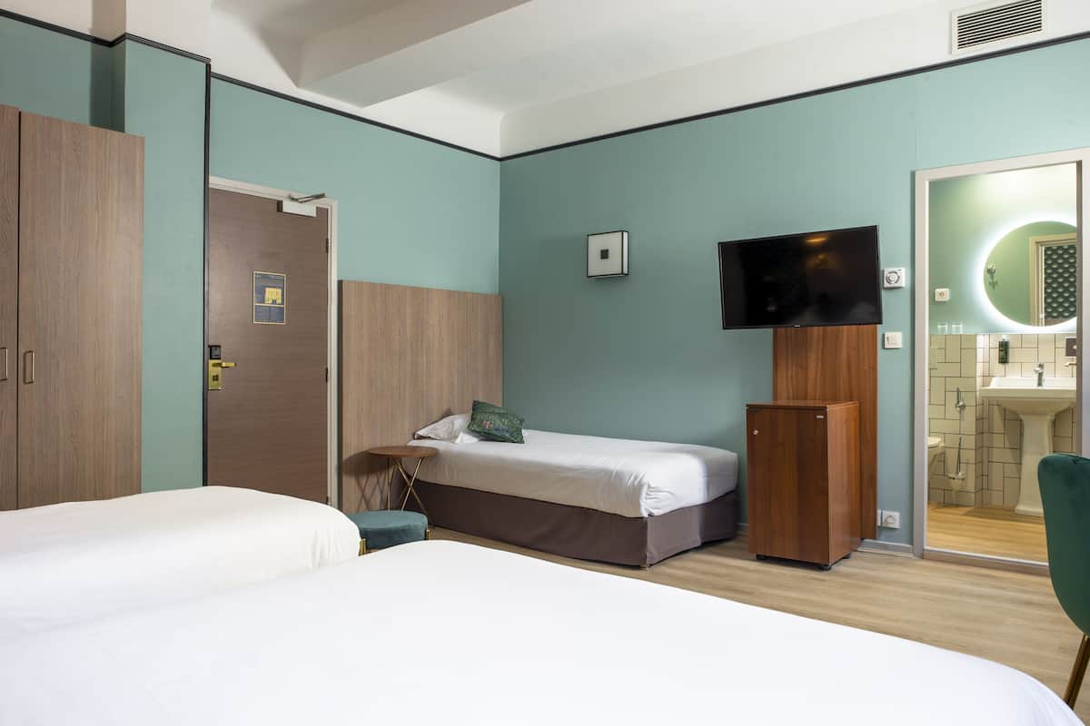 A hotel room with two beds, a television, a mirror, and a small refrigerator.