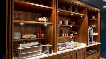 A buffet setup with various food items, a toaster, and a coffee machine.