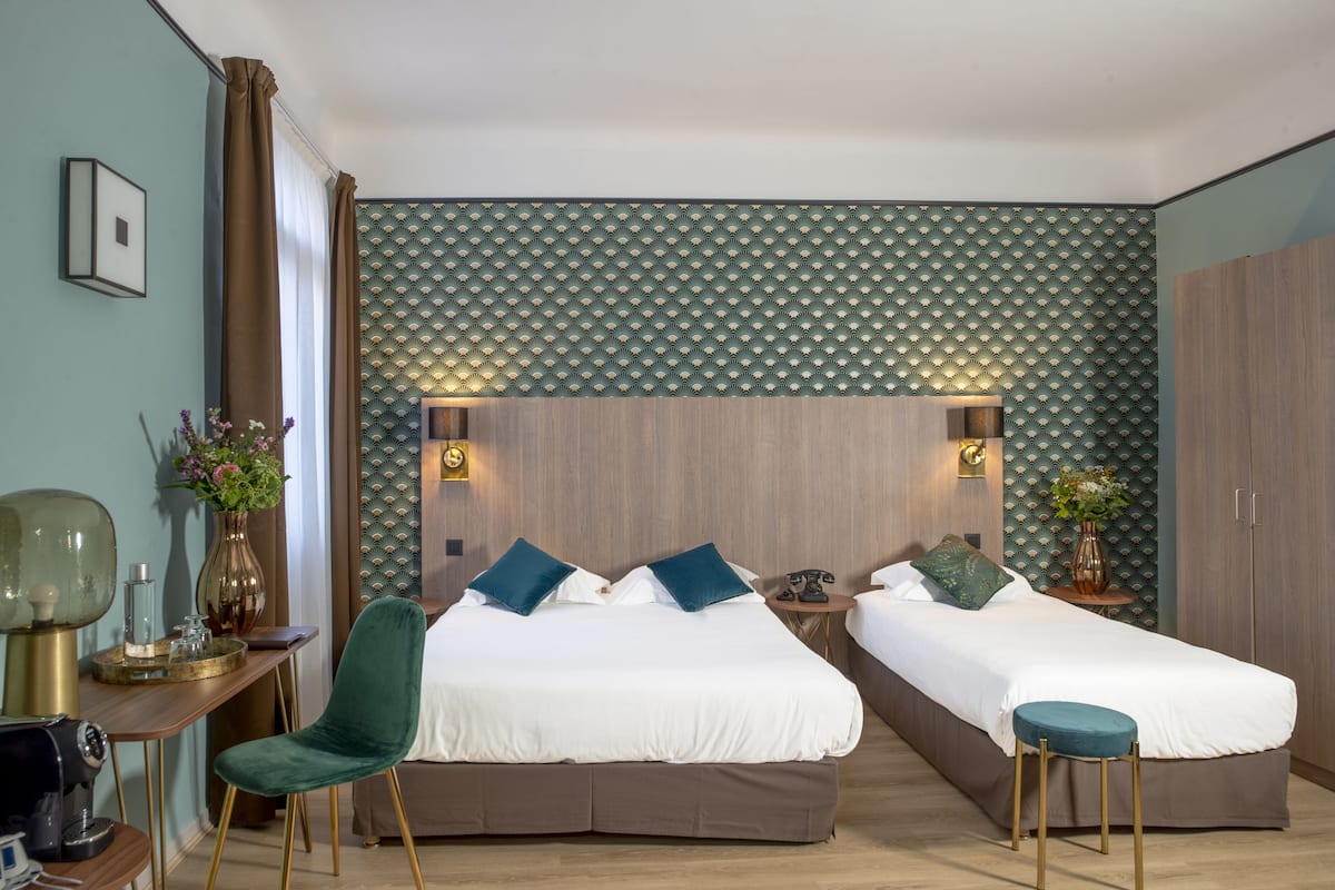A modern hotel room with two beds, a desk, and a chair.