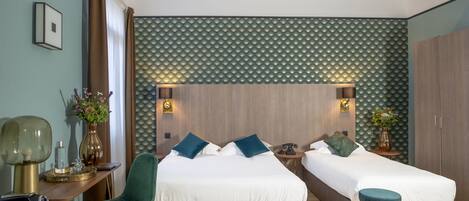 A modern hotel room with two beds, a desk, and a chair.