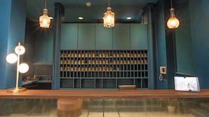 Een bar met een houten toonbank, meerdere hangende hanglampen en een plank met flessen.