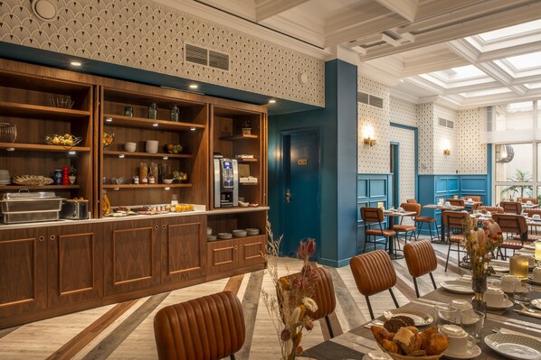 Un espace de restauration moderne dans un hôtel, avec des comptoirs de buffet en bois, des sièges confortables et un plafond décoré de motifs.