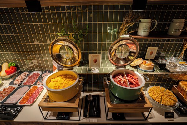 Un buffet proposant une variété de plats, notamment des viandes, des fromages et une grande tarte.