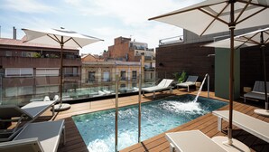 Un espace piscine aménagé sur le toit, avec des chaises longues et des parasols.