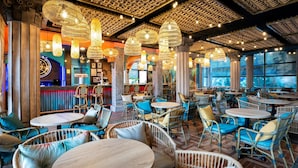 A restaurant with wicker furniture, hanging lights, and a bar area. - PortAventura Hotel Caribe - Includes unlimited access to PortAventura Park & 1 day access to Ferrari Land (Salou)