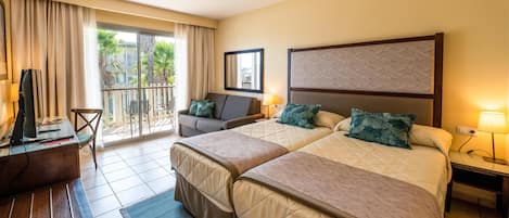 Quarto de hotel com duas camas, uma escrivaninha, uma cadeira e uma varanda com vista para palmeiras.