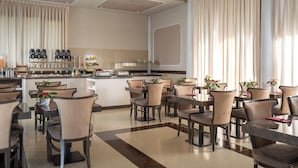 Un comedor moderno con una isla central, diferentes disposiciones de asientos y una cocina al fondo.