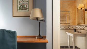 Un bagno con lavandino, specchio, portasciuga e una stampa botanica incorniciata appesa al muro.