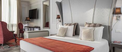 Una habitación de hotel con una cama grande, un escritorio, un televisor y una silla roja.