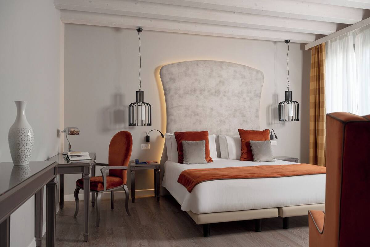 A modern hotel room with a large bed, a desk, and two chairs.