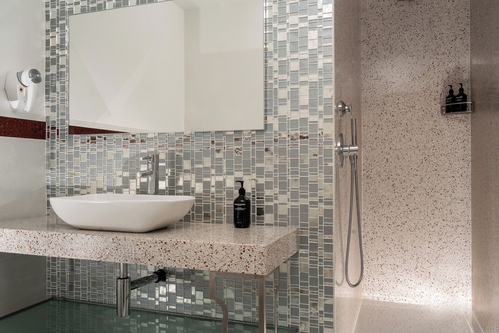 Et moderne badeværelse med en hvid vask, en glas brusekabine og et flisebeklædt backsplash.