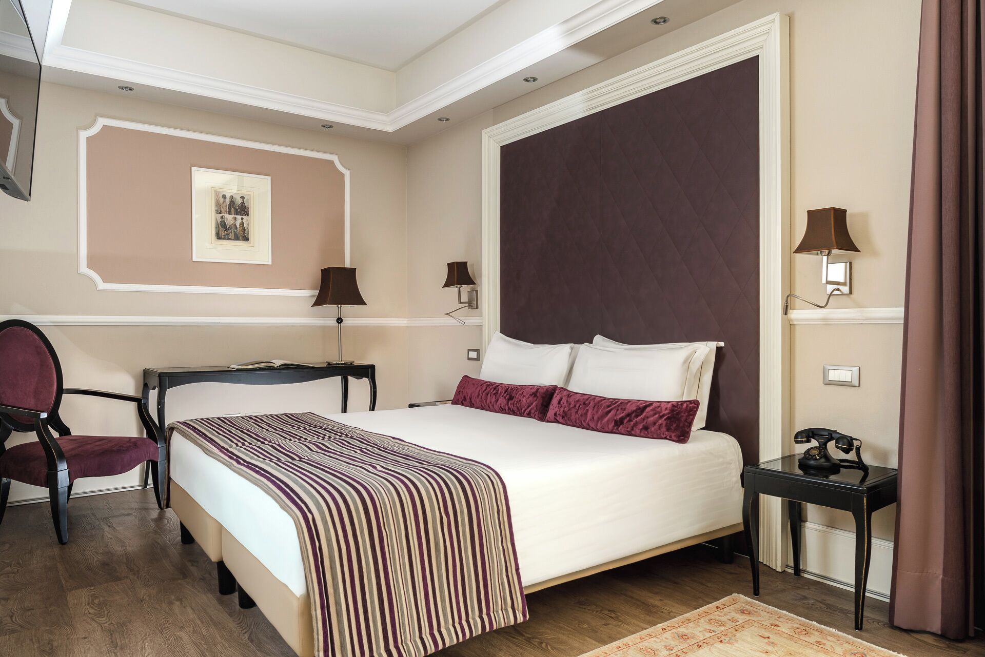 Une chambre d’hôtel avec un grand lit, un bureau, deux chaises, une lampe et un tableau encadré au mur.