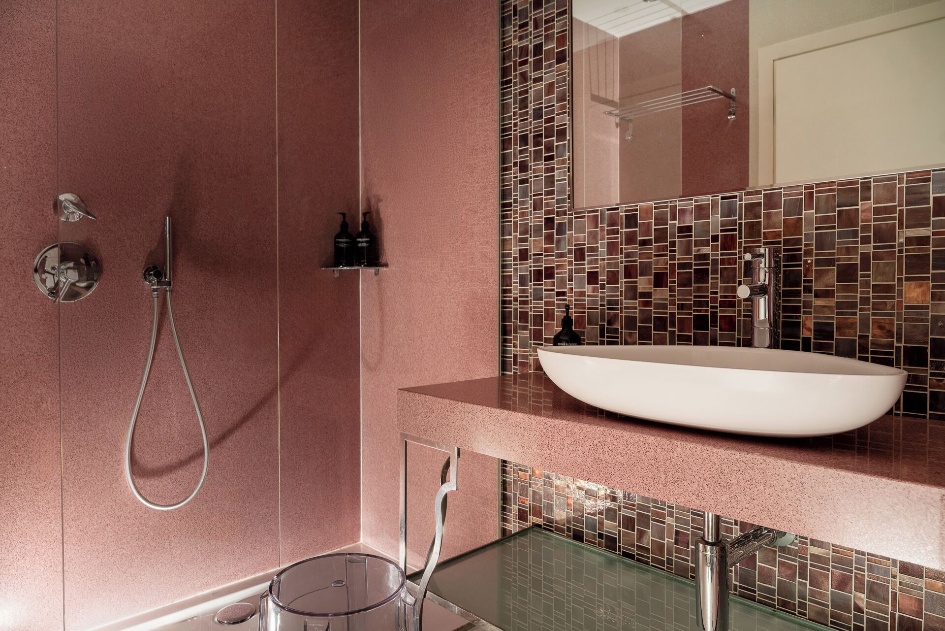 A modern bathroom with a large mirror, a vessel sink, and a shower with a handheld showerhead.