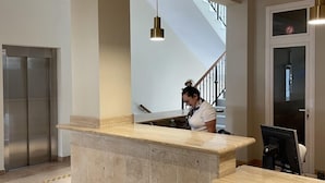 A reception area with a marble counter, a staircase, and an elevator. - Hotel Almijara – Mares (Almunecar)
