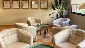 A lounge area with beige armchairs, a checkered floor, and framed artwork on the wall. - Hotel Almijara – Mares (Almunecar)
