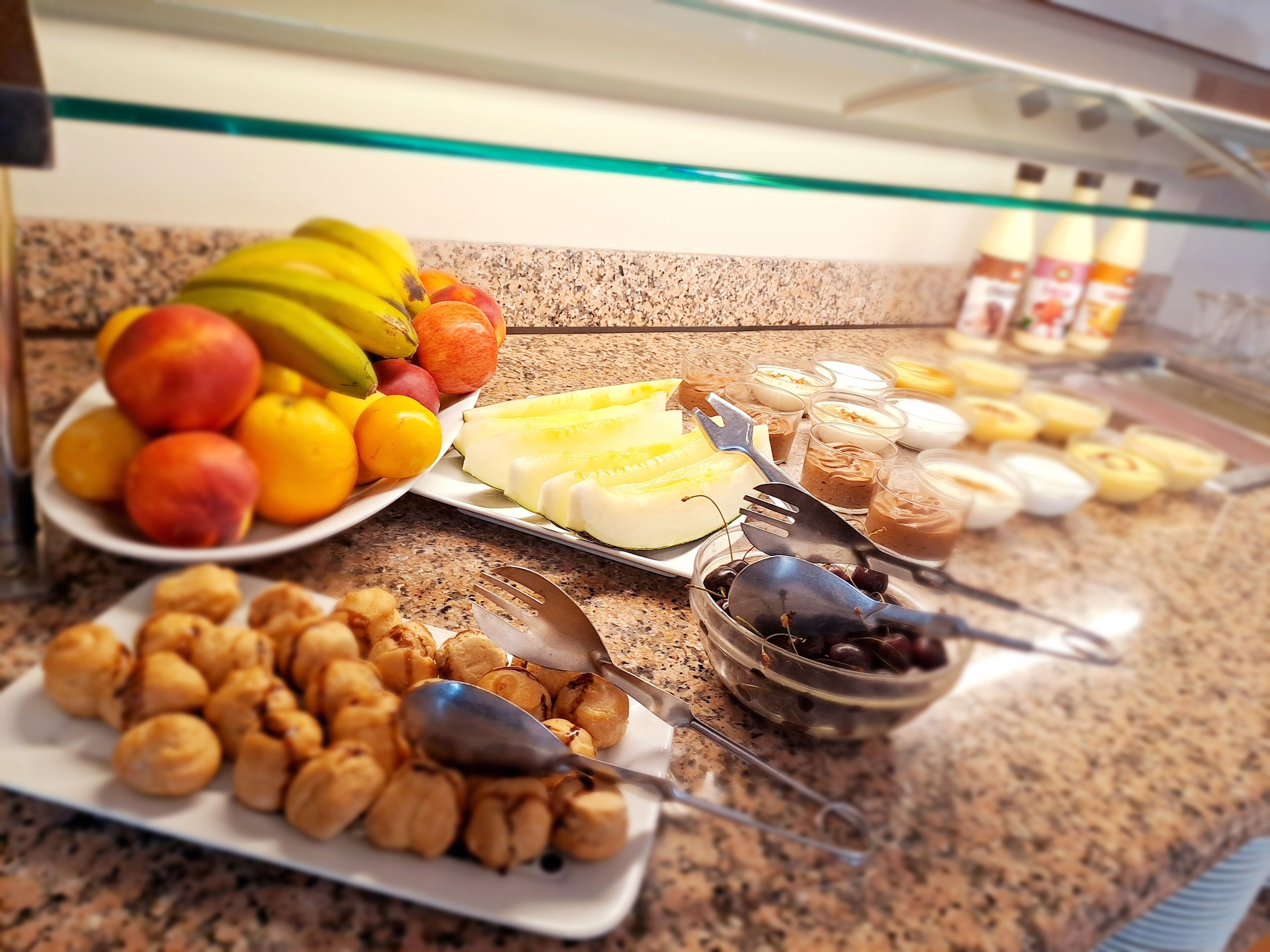 A buffet with various food items including fruits, pastries, and desserts.