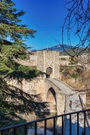 Un puente de piedra con un arco de entrada que conduce a una torre fortificada.