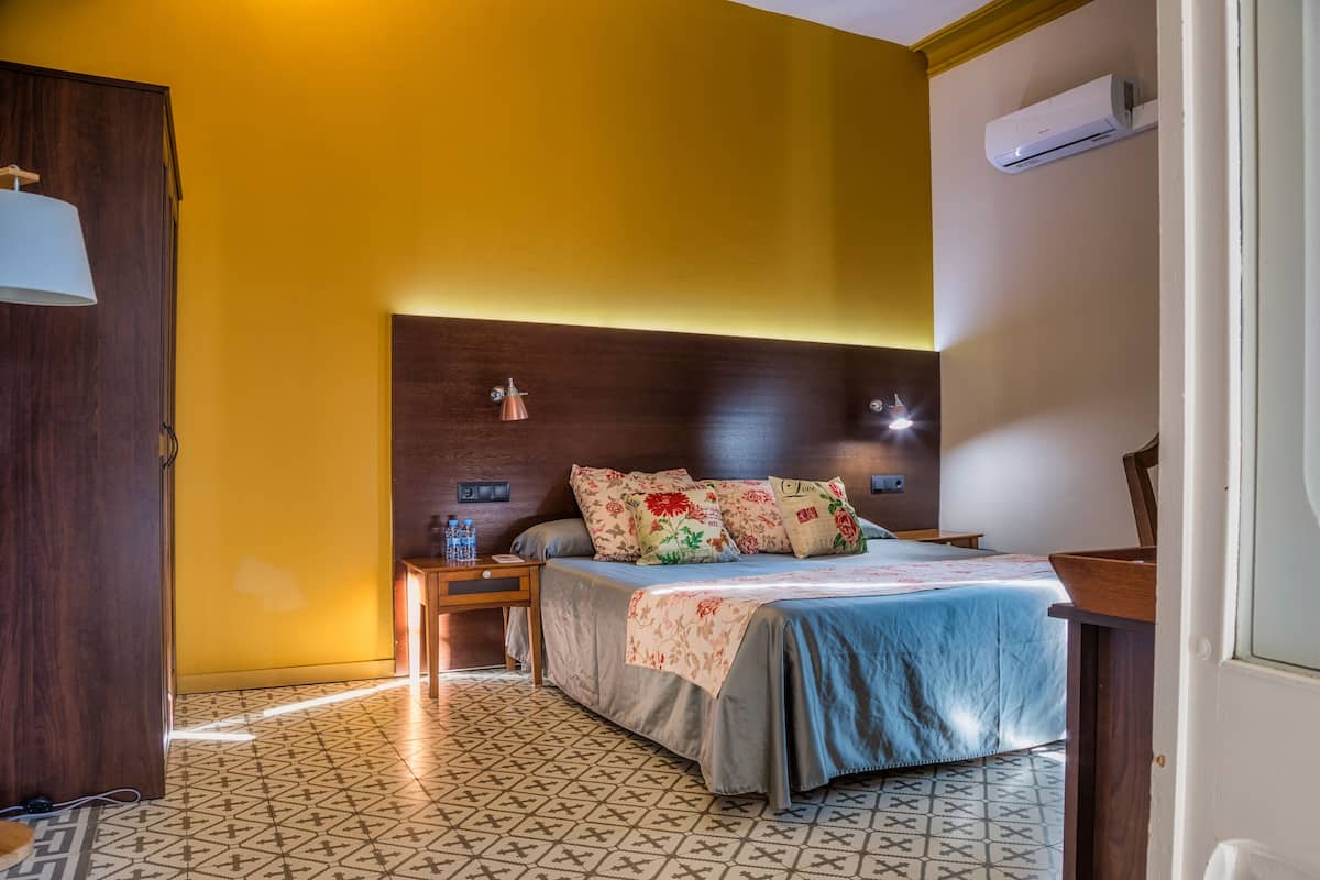 A bedroom with a bed, nightstand, and an air conditioning unit.