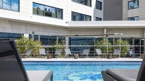 Un espace piscine moderne avec des chaises longues et une piscine à l’eau d’un bleu limpide.